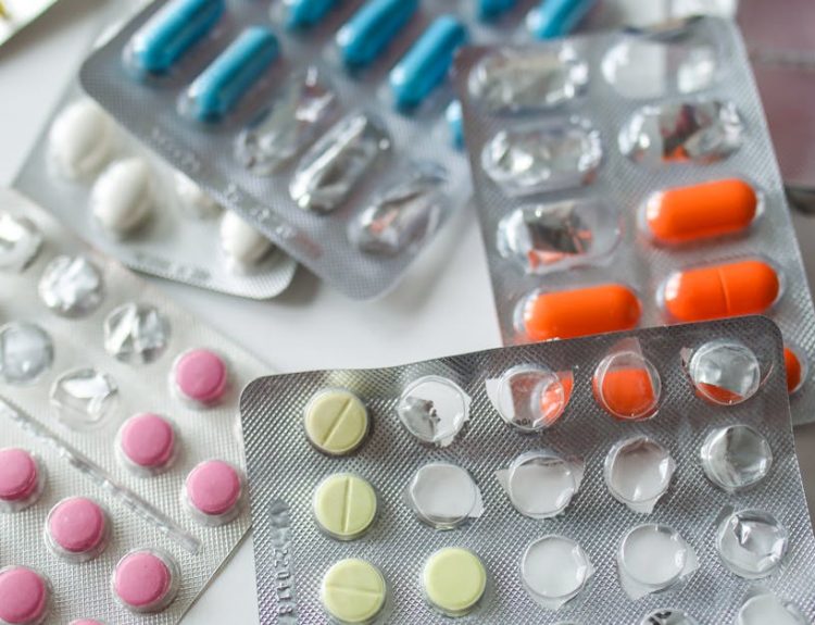 Assorted colorful blister packs of pills and capsules on a white surface.