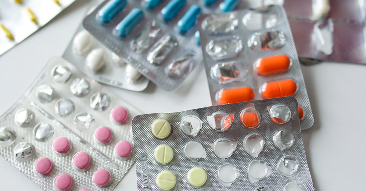 Assorted colorful blister packs of pills and capsules on a white surface.