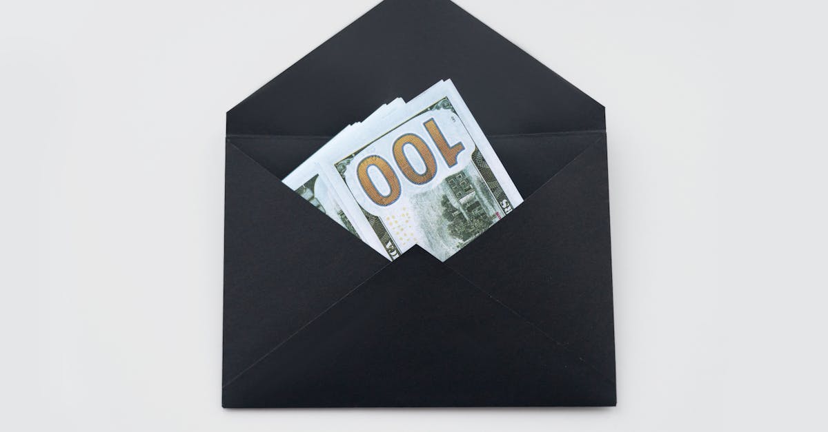 Hundred dollar bills partially visible in an open black envelope on a white background.