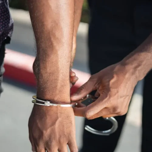 Close-up of a police officer handcuffing a suspect outdoors, enforcing law.