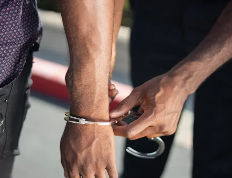 Close-up of a police officer handcuffing a suspect outdoors, enforcing law.