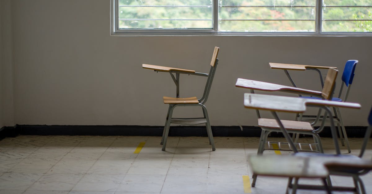 Quiet empty classroom interior with school desks by a large window.