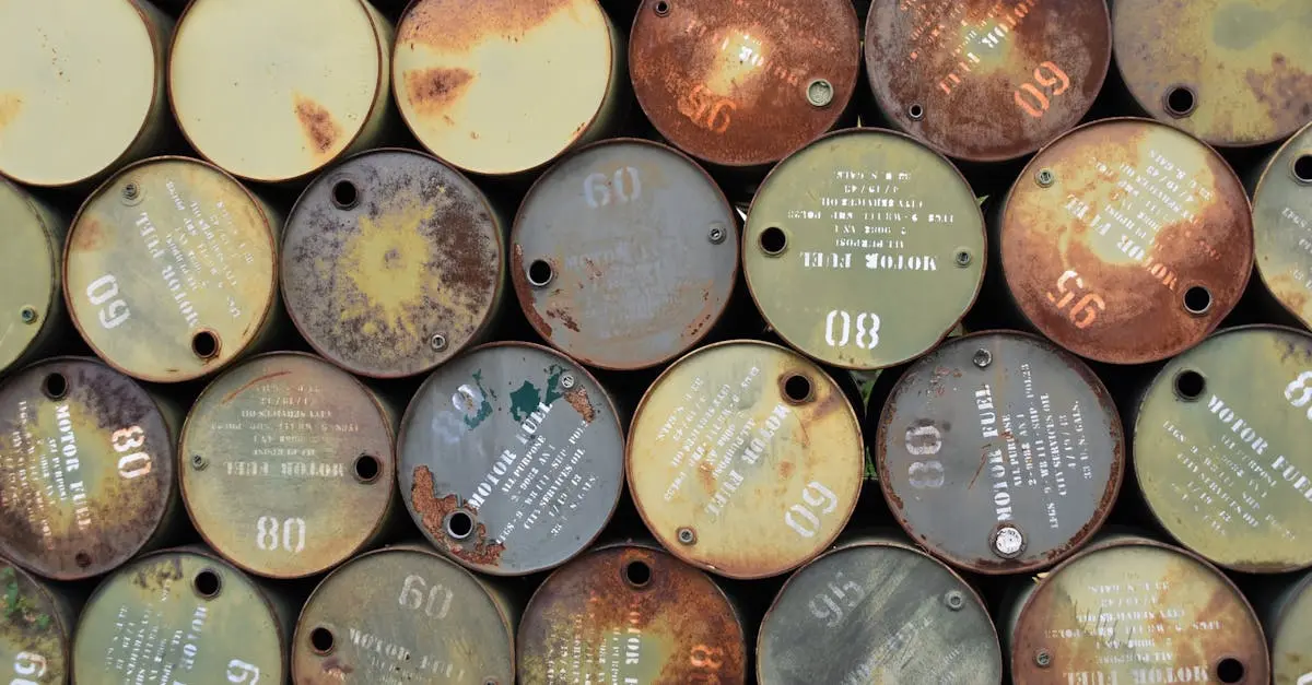 Pile of old, rusty oil barrels stacked outdoors with visible labels and numbers.