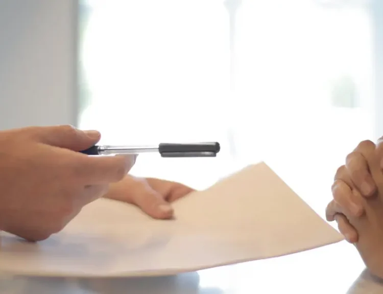 Close-up of a contract signing with hands over documents. Professional business interaction.